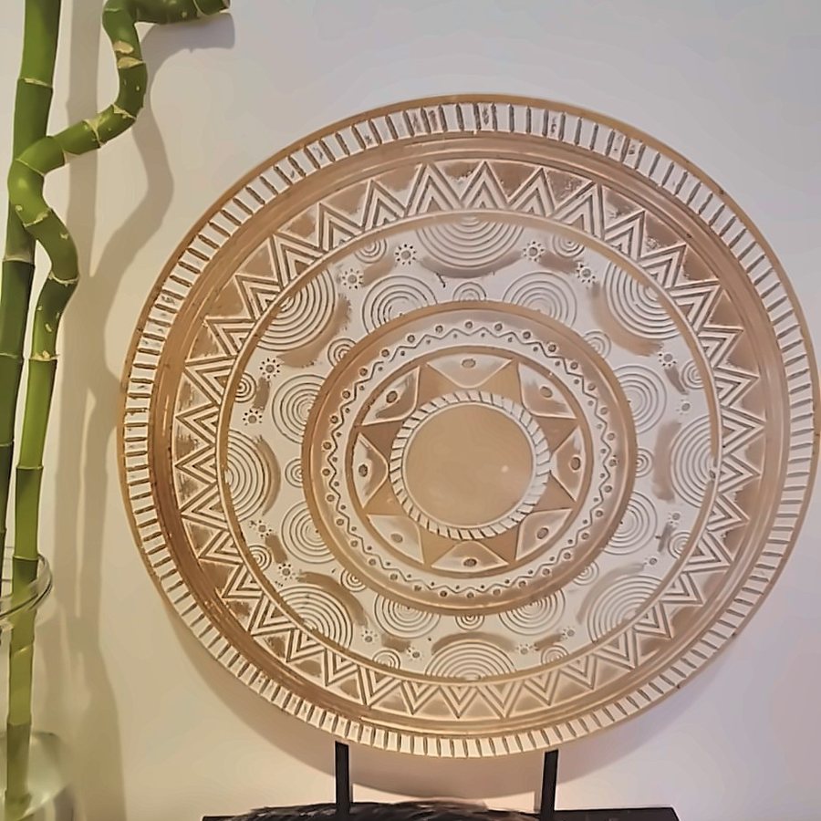 Mandala esculpida em madeira sobre um suporte, no espaço de atendimento de Juliana Vilaça