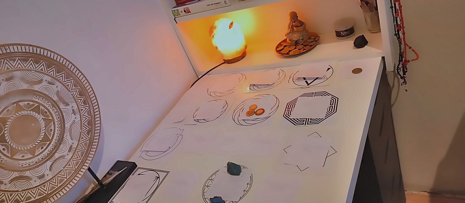 Mesa radiônica montada com gráficos, cristais e velas, no espaço de trabalho de Juliana Vilaça
